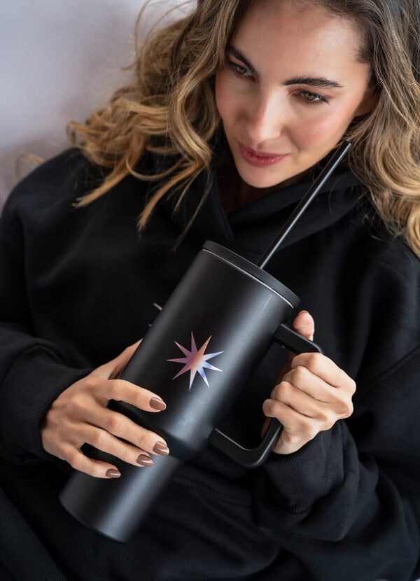 A sleek black tumbler with a colorful starburst design, perfect for hot and cold beverages, featuring a straw and handle for convenient use and portability.