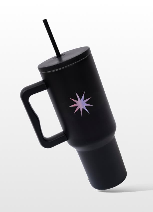 Stylish black reusable travel mug with lid and straw, featuring a purple starburst design, perfect for coffee or beverages on the go.