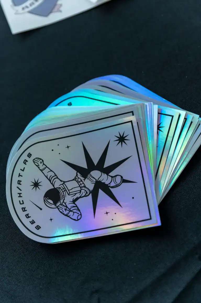 Holographic sticker featuring an astronaut reaching towards a star, with a compass design. Perfect for space-themed collections, decals, and space exploration enthusiasts, showcasing vibrant, reflective colors.